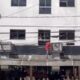 Homem se desloca pelo lado de fora de prédio, entre janelas
