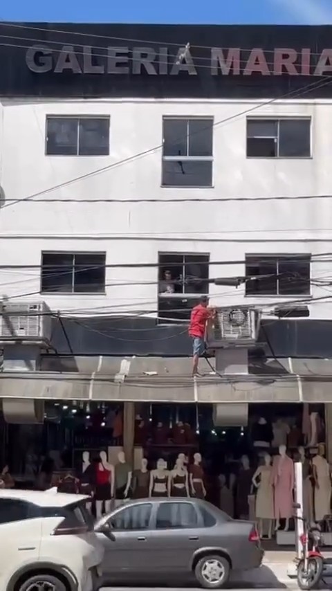 Homem se desloca pelo lado de fora de prédio, entre janelas